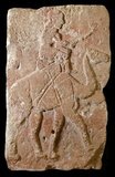 This bas-relief was excavated in northern Syria at the site of Tell Halaf, the capital of a small independent city-state known as Guzana, which was conquered by the Assyrians in the late 9th century BC.<br/><br/>

More than two hundred such stone reliefs (styled orthostats) decorated the façade of a temple-palace built in the 10th century BCE by a local ruler named Kapara. He reused the blocks from one or more pre-existing structures and carved an inscription in cuneiform on each one statings, 'Palace of Kapara, son of Hadianu'. The blocks were placed so that limestone ones painted red alternated with others of black basalt.<br/><br/>

In this image, a rider sits atop the hump of a dromedary camel, driving it on with a staff. Crossed leather or cloth bands fasten the saddle to the animal. The image represents an Arab caravan trader. The domestication of dromedaries shortly before the beginning of the first millenium BCE made the caravan trade possible. This relief from Tell Halaf may be the earliest representation of such a dromedary rider.